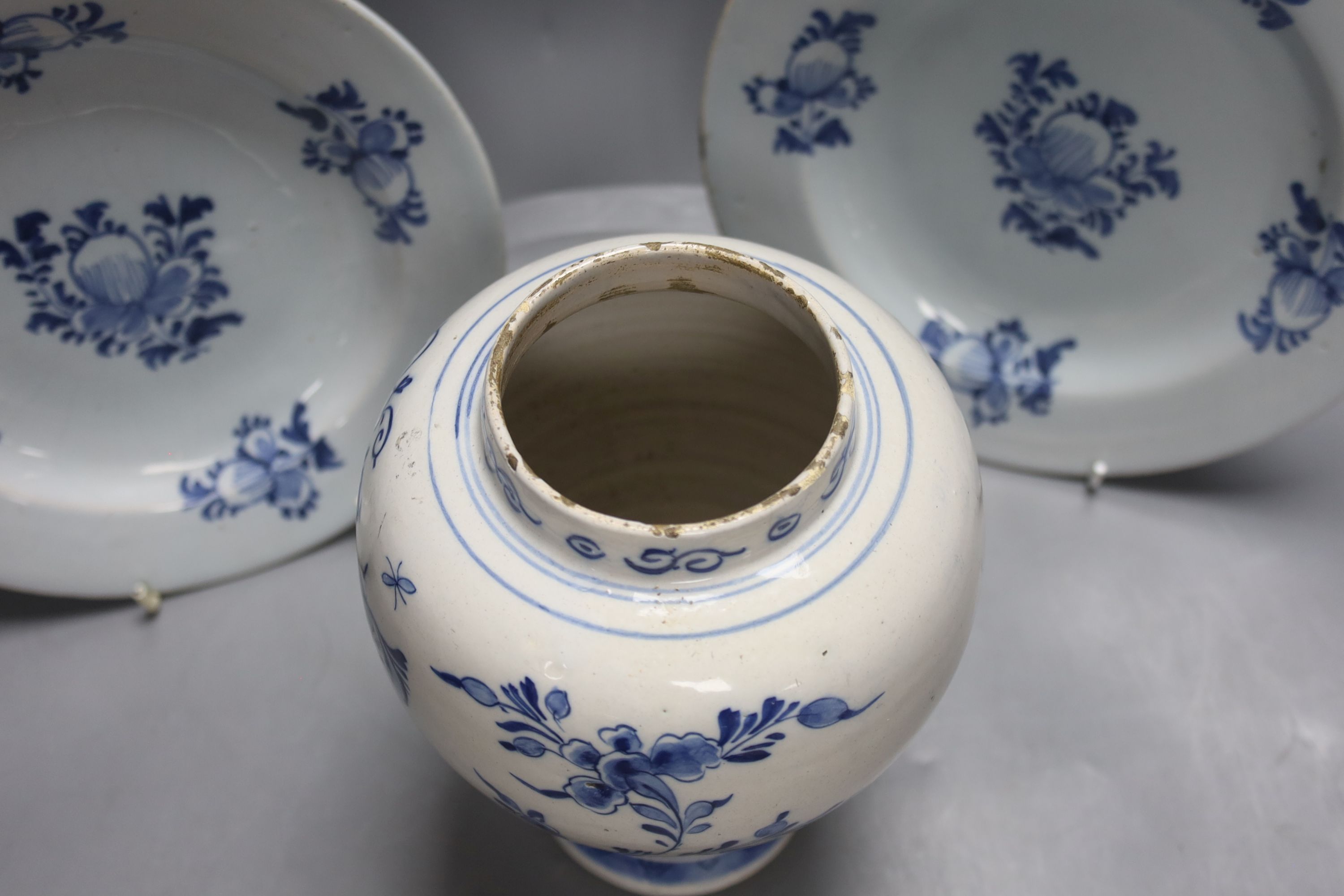 A mid-18th century Dutch Delft flower and fence-decorated blue and white baluster vase, a similar plate and a pair of English delft plates, H 20cm (vase)